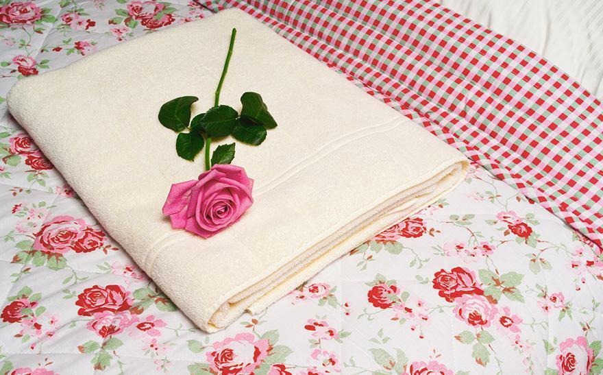 róża i ręcznik na łóżku